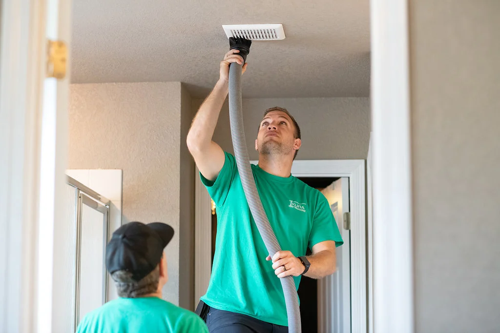 Technician performing air duct cleaning in a residential home